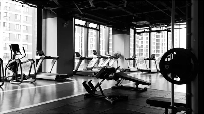 Treadmills, an elliptical and a bench along a window wall in a high-rise amenity gym