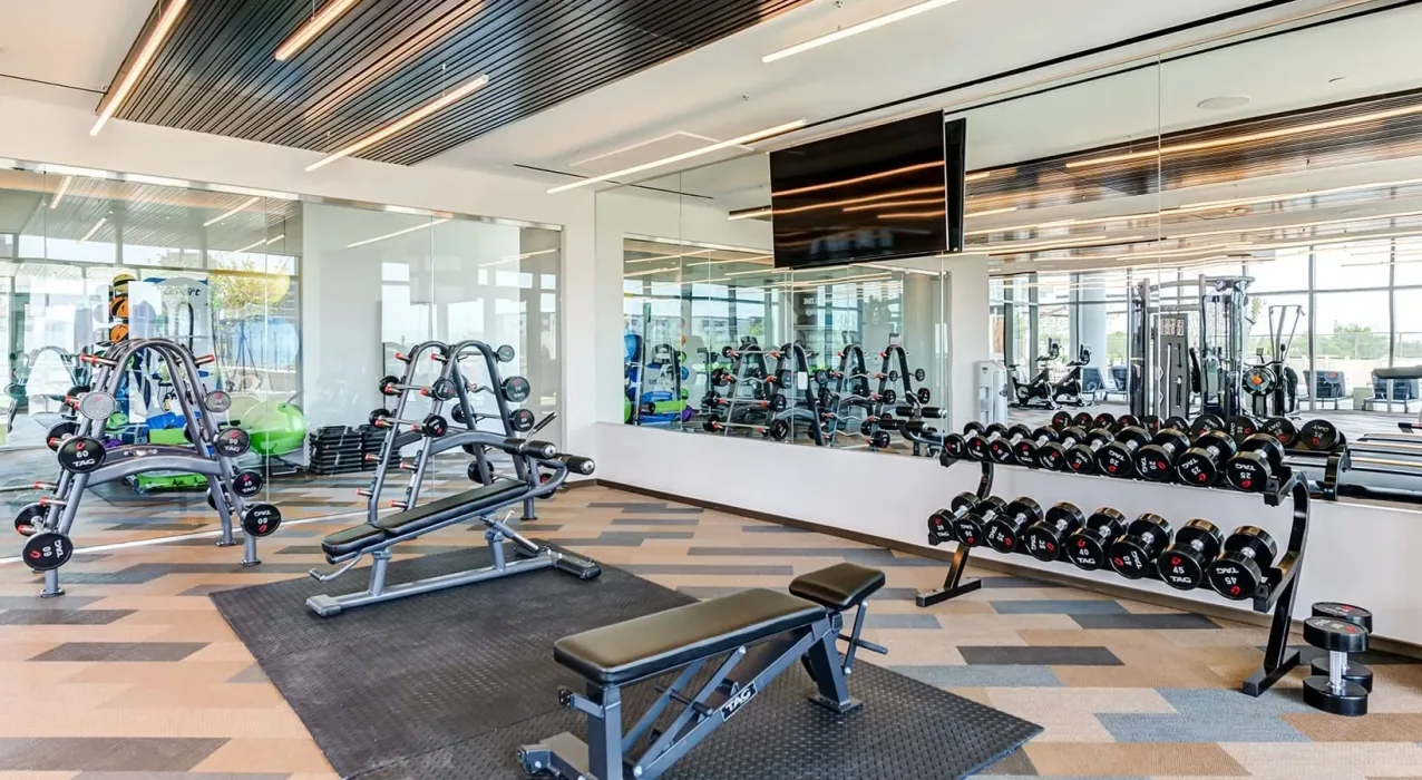 Apartment amenity gym in Dallas, Texas, with TAG plate trees, benches and a rubber hex dumbbell rack