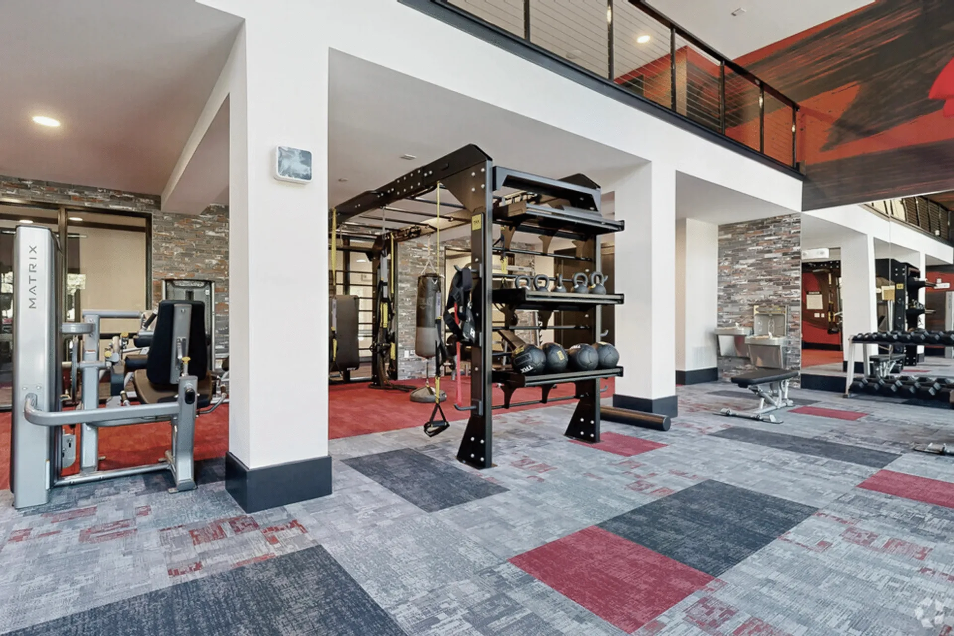 Two-story apartment amenity gym in Birmingham, Alabama, with a TKO functional rig, heavy bag and carpet tile