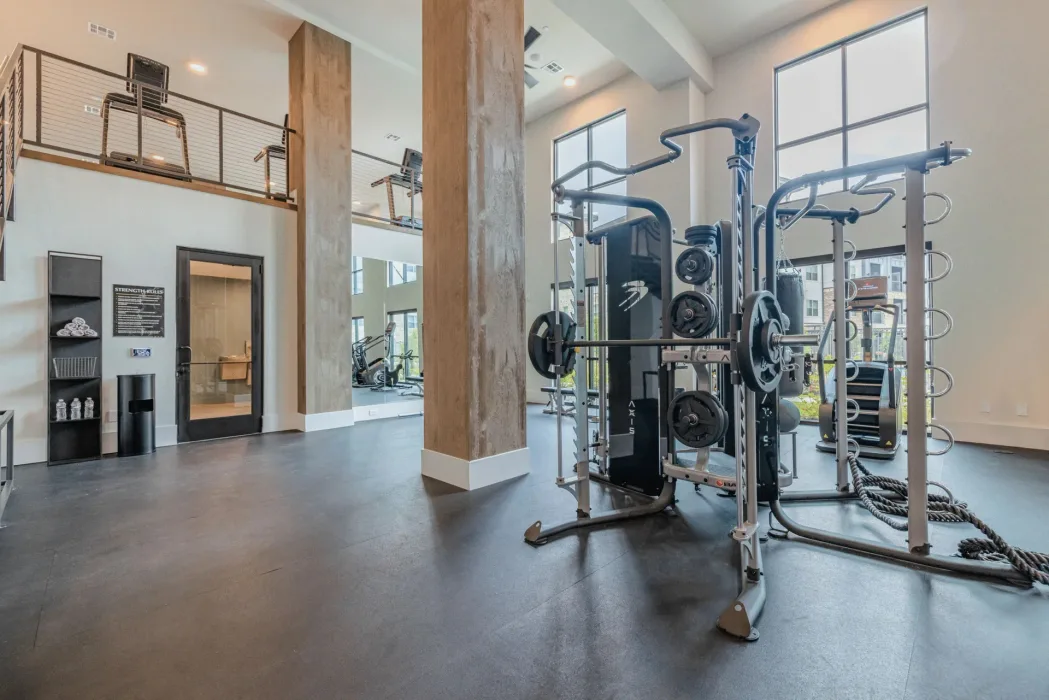 Double-height apartment gym in Colorado with an Axis functional trainer, heavy bag, battle ropes and rubber flooring