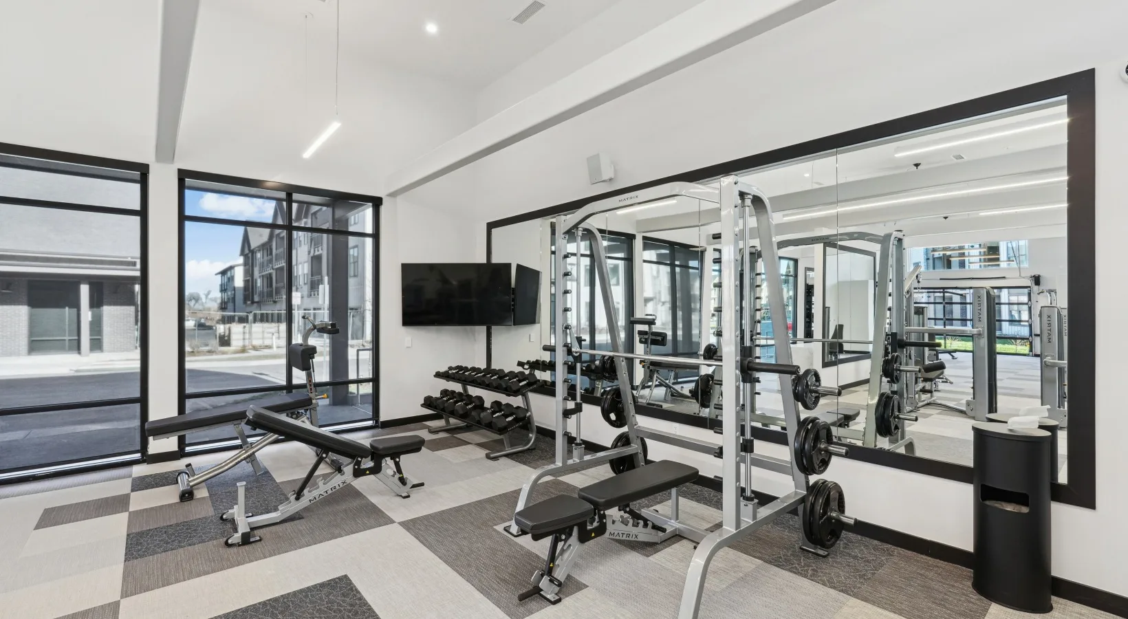 Apartment community gym in Colorado with a Matrix Smith machine, adjustable benches and a dumbbell rack