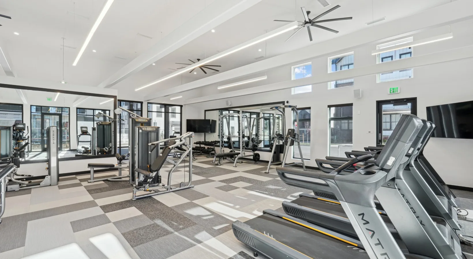 Apartment community fitness room in Colorado with Matrix treadmills, a Smith machine and carpet tile flooring