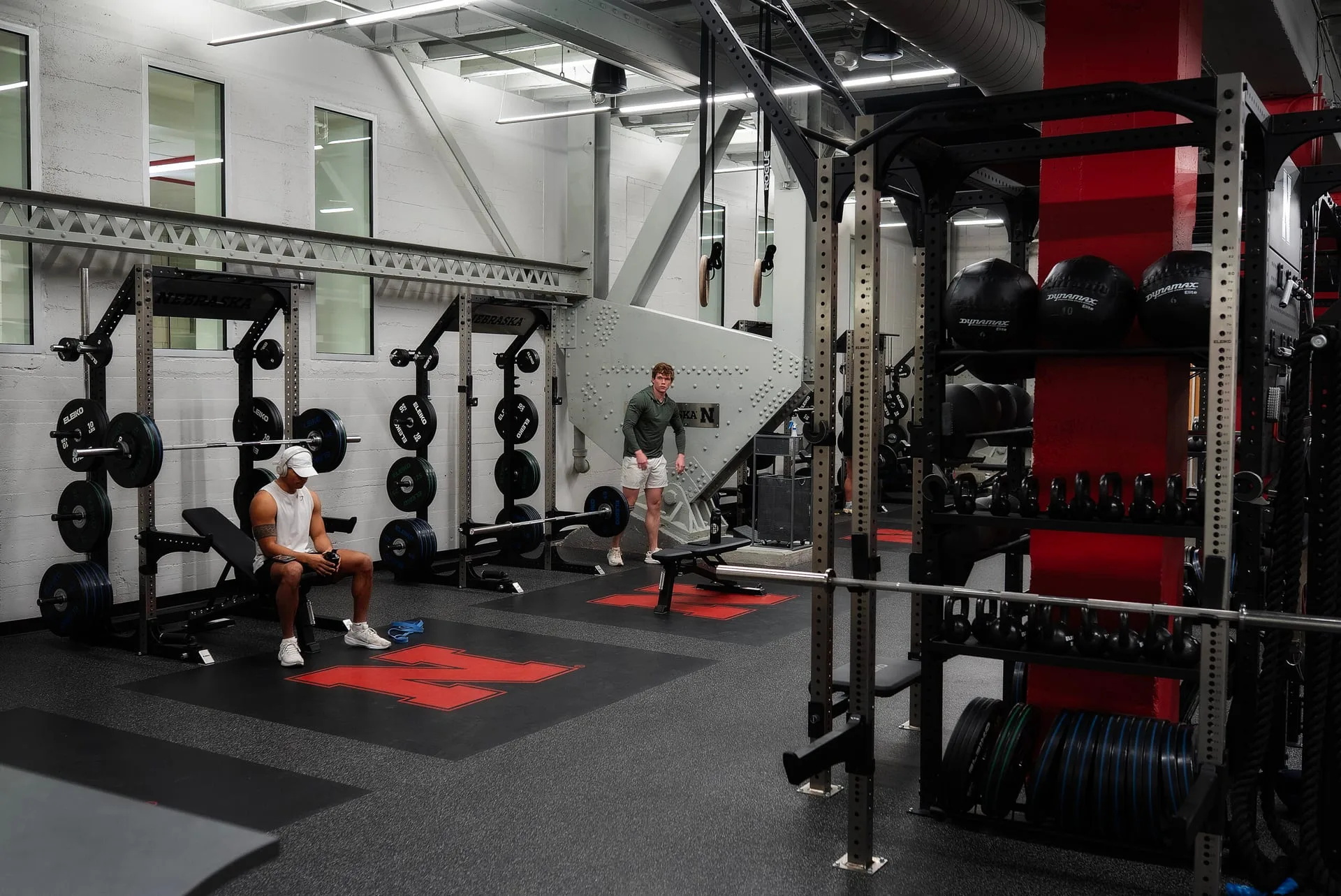 Rubber flooring installed across a college weight room, with a separate platform area