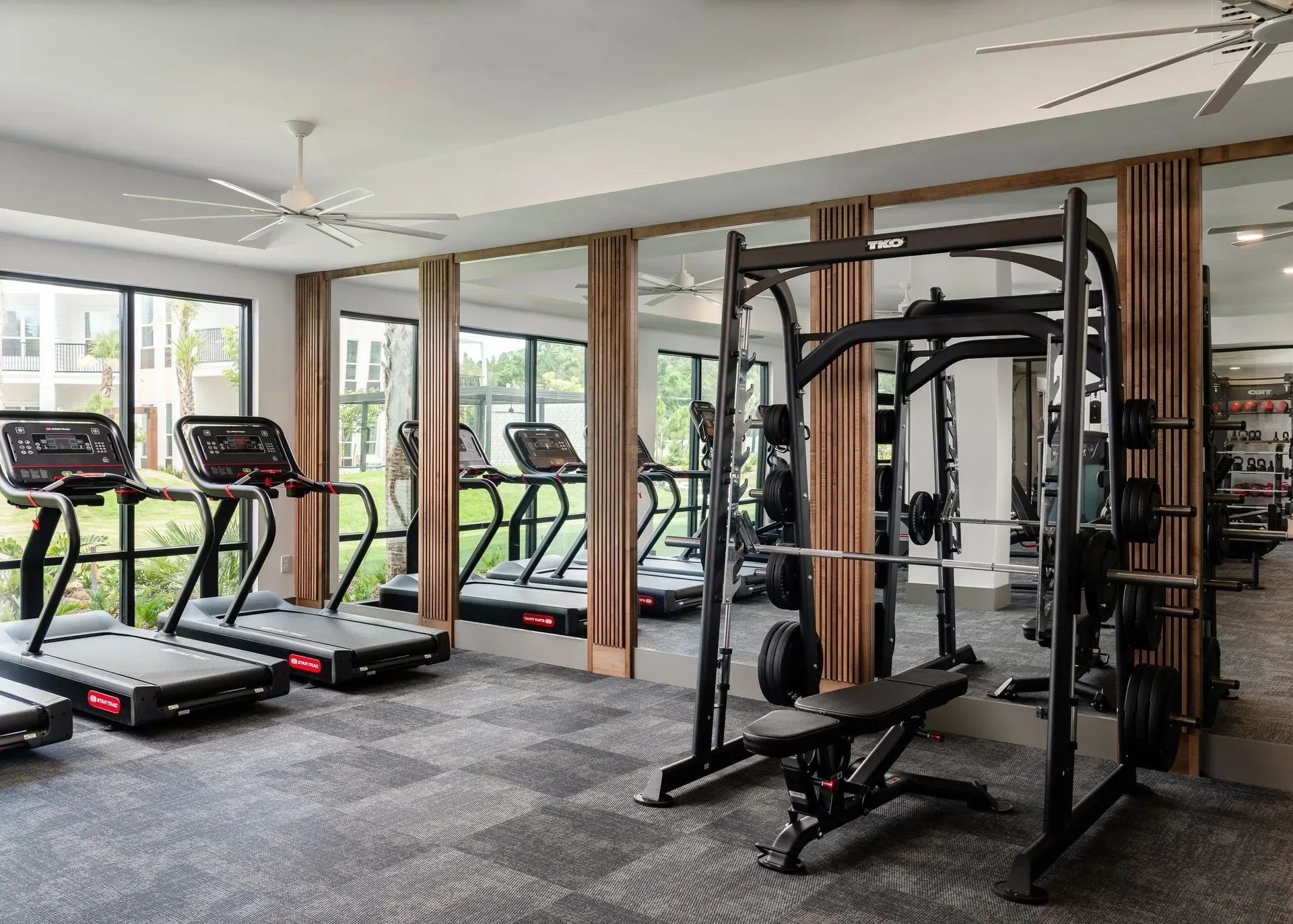 Apartment amenity gym in Lutz, Florida, with Star Trac treadmills, a TKO Smith machine and carpet tile flooring