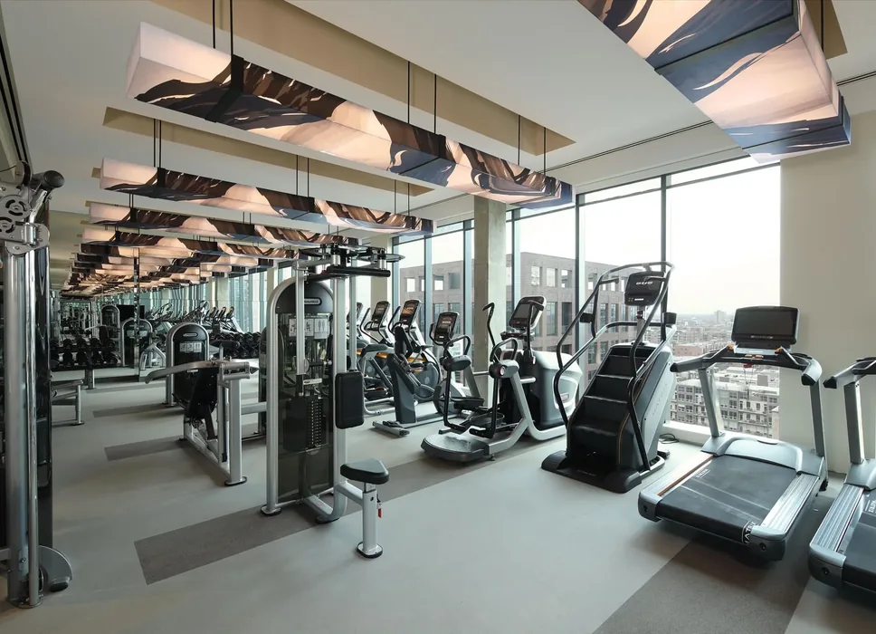 Top-floor apartment gym in Illinois with Matrix treadmills, a stair climber, ellipticals and a cable machine