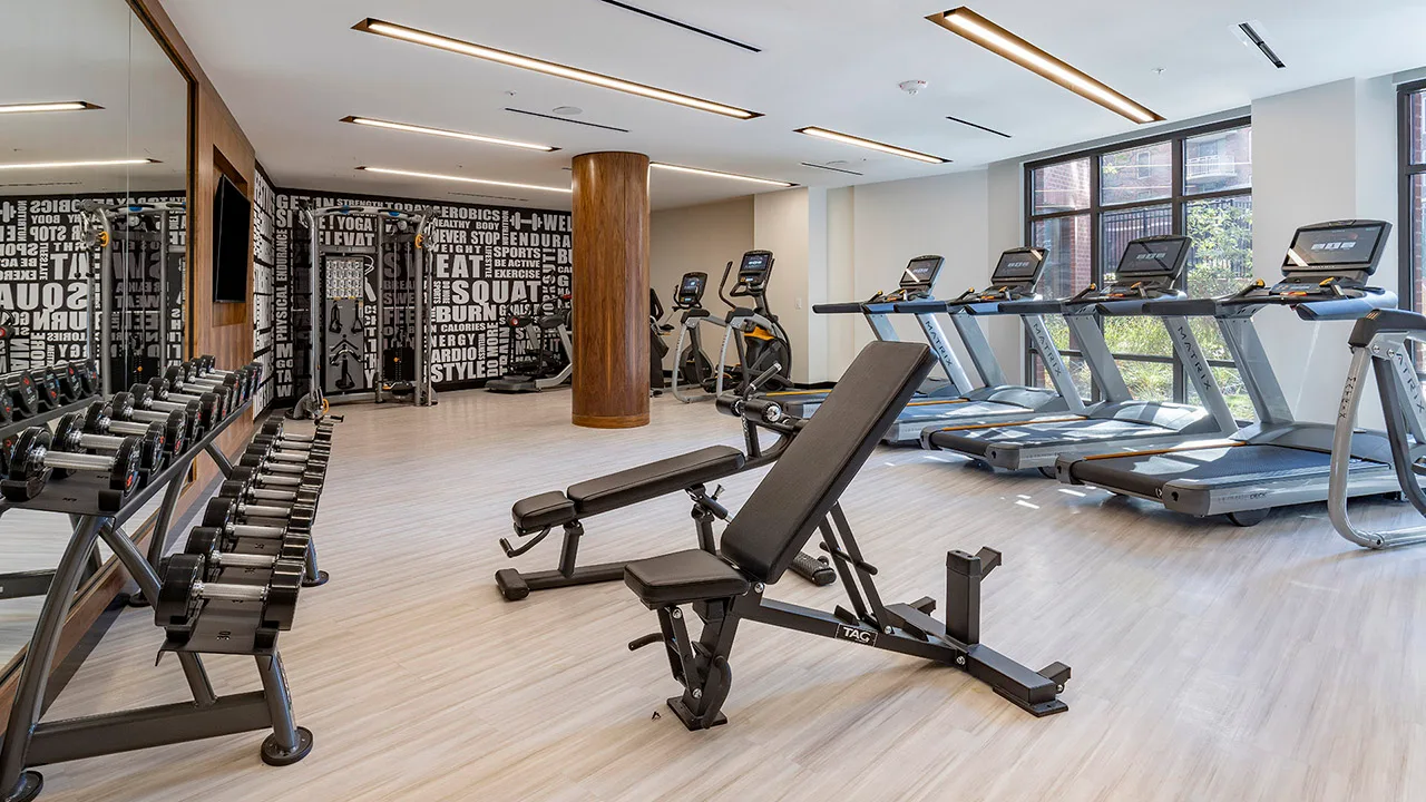 Apartment amenity gym in Bethesda, Maryland, with a dumbbell rack, TAG benches and Matrix treadmills