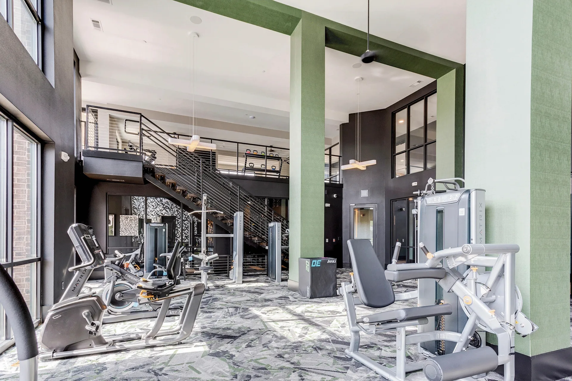 Two-story apartment amenity gym in Mooresville, North Carolina, with Matrix bikes and leg press machines