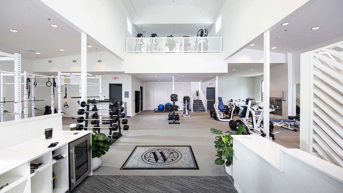 Community fitness center in Tennessee with white power racks, tiered dumbbell racks and cardio on the mezzanine