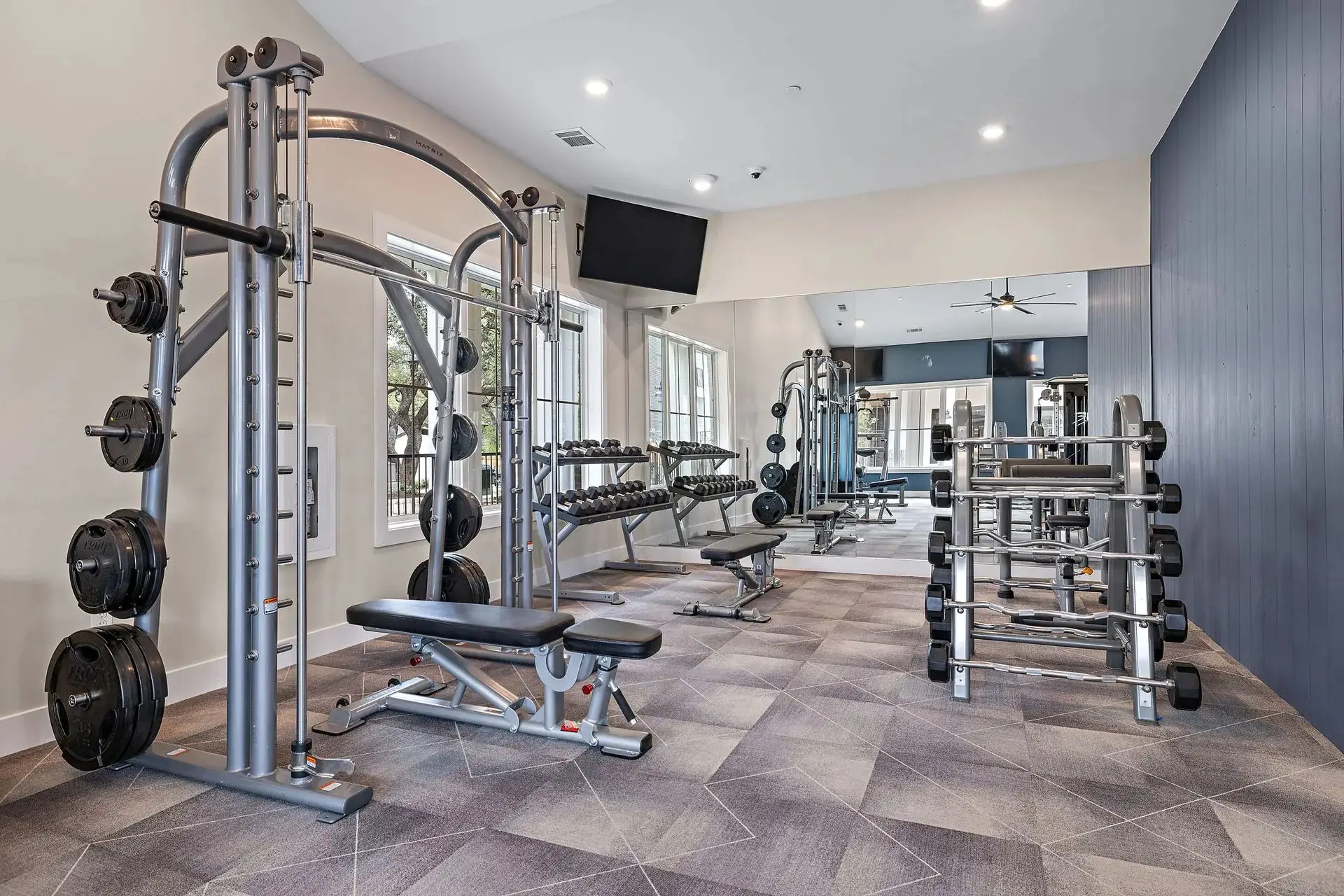 Strength area in an Austin, Texas apartment gym with a Matrix Smith machine, plate storage and barbell racks