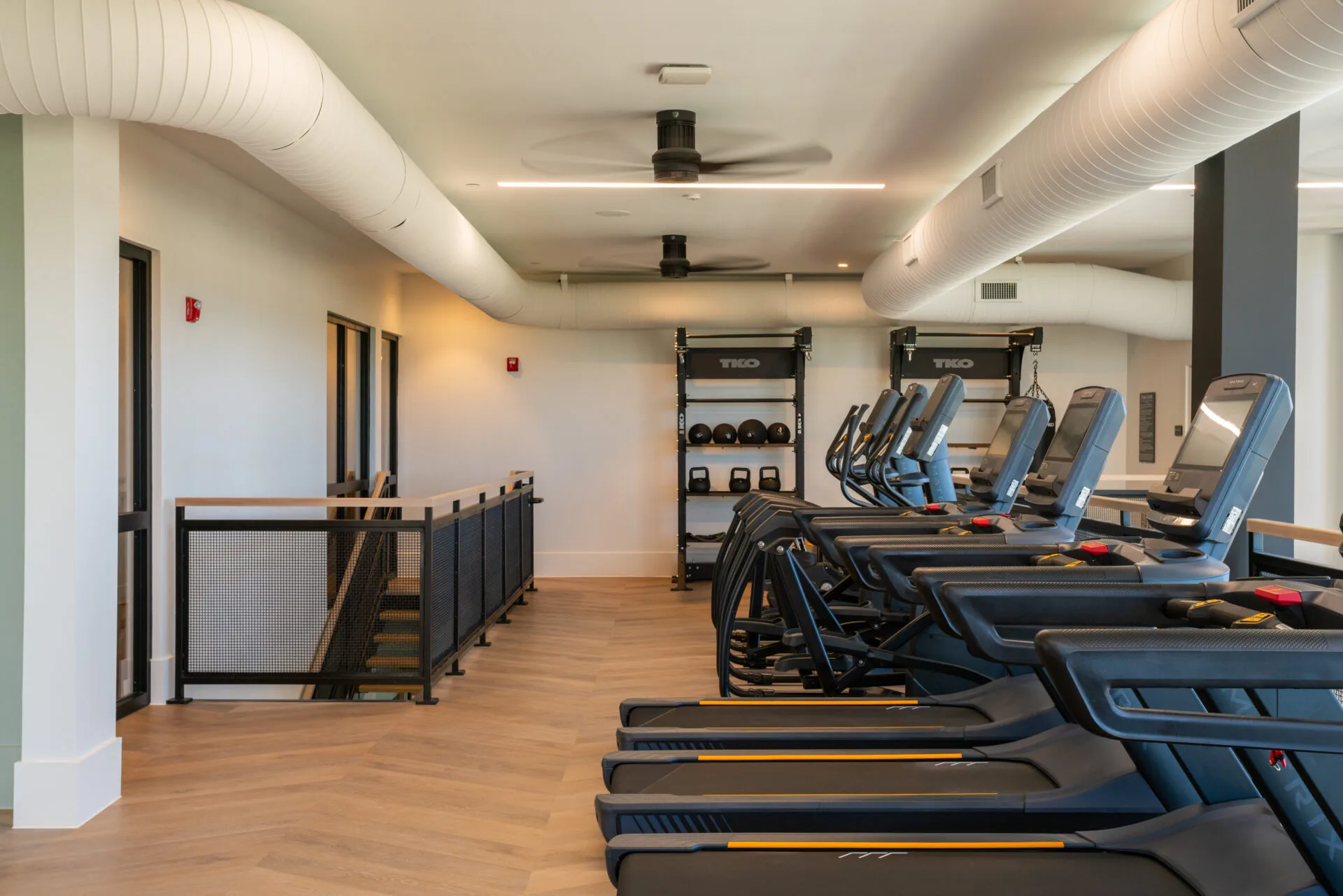 Cardio deck in a Texas apartment gym with Matrix treadmills, ellipticals and a TKO medicine-ball rack