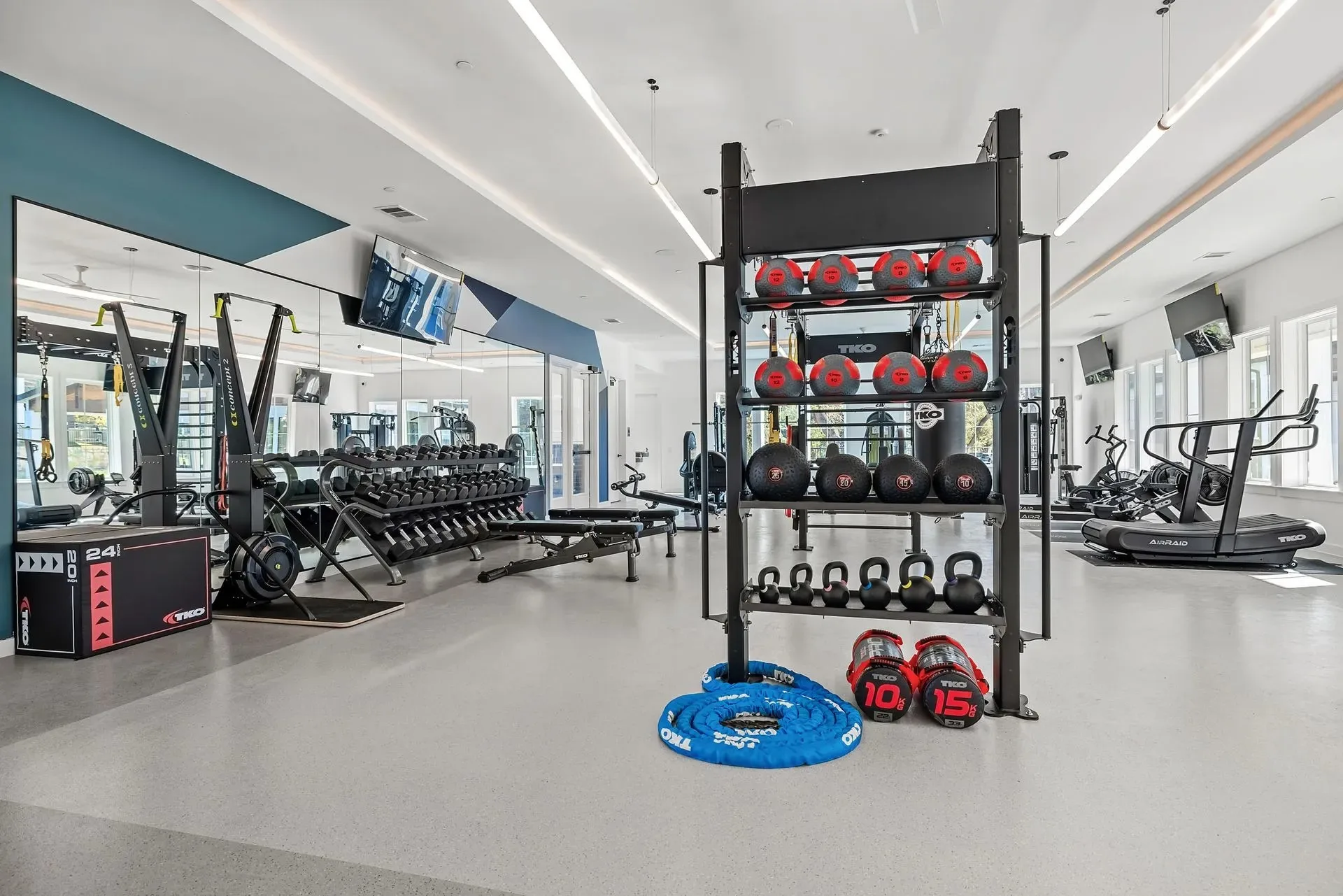 Apartment amenity gym in Austin, Texas, with a TKO medicine-ball rack and a curved AirRaid treadmill