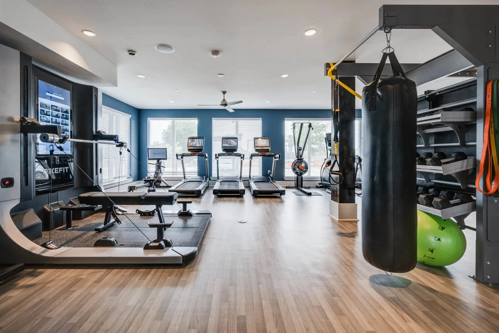 Apartment gym in Little Elm, Texas, with a heavy bag, treadmills, an AI trainer, a rower and dumbbell racks