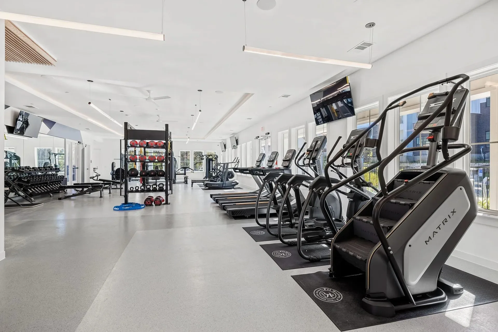 Apartment fitness center in Austin, Texas, with a Matrix stair climber and treadmills on polished concrete