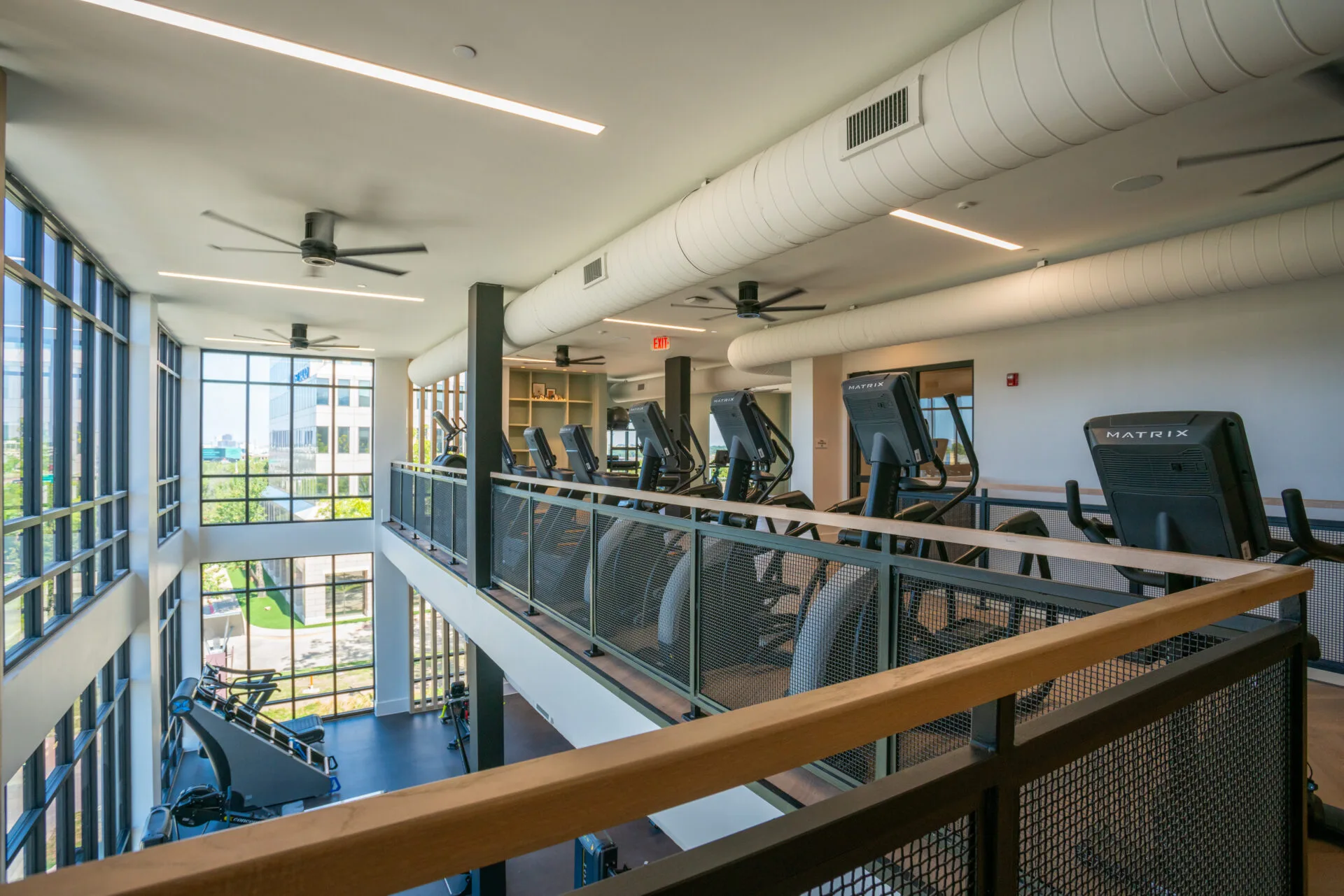 Upstairs cardio floor in a Texas apartment amenity gym, with treadmills beside a window wall