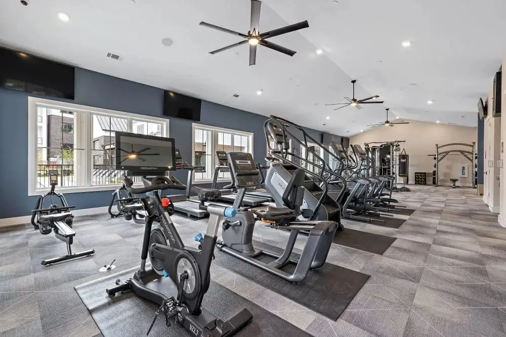 Cardio room in a Texas apartment gym with FreeMotion indoor cycles, treadmills, a stair climber and recumbent bikes