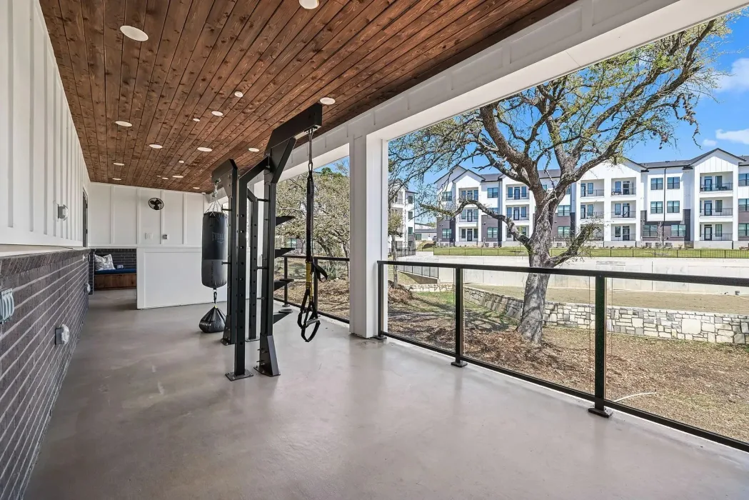 Covered outdoor training deck at a Texas apartment community with a heavy bag and suspension trainers on a rig