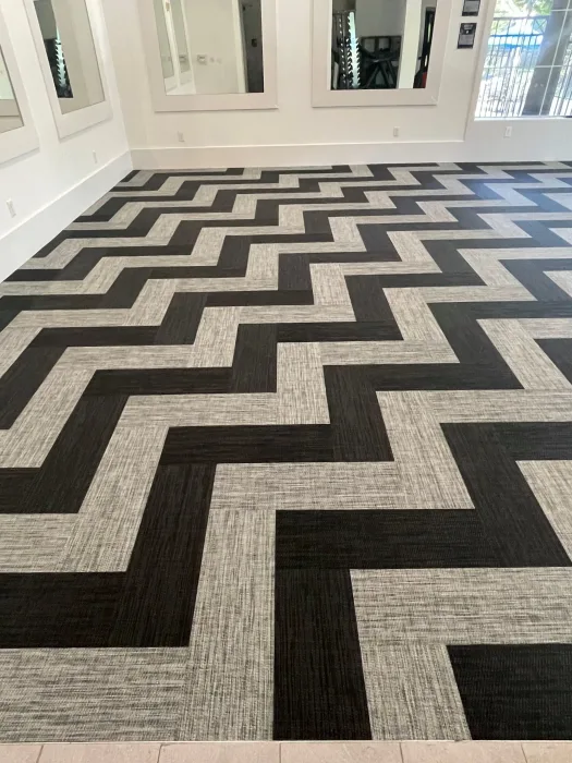 Chevron carpet tile in charcoal, black and oatmeal running the length of an amenity fitness room