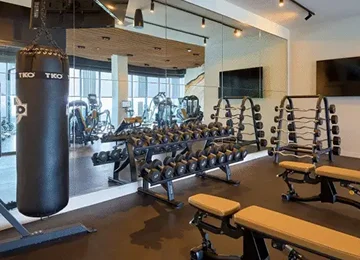 Apartment amenity gym with a TKO heavy bag, a two-tier dumbbell rack and benches on rubber flooring