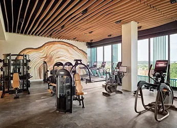 Fitness floor with selectorized strength machines, ellipticals and recumbent bikes under a slatted wood ceiling