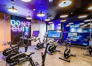 Indoor cycling studio with Echelon Connect bikes and individual screens under colored accent lighting