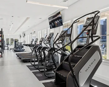 Cardio row in a commercial fitness center with a Matrix stair climber, ellipticals and treadmills