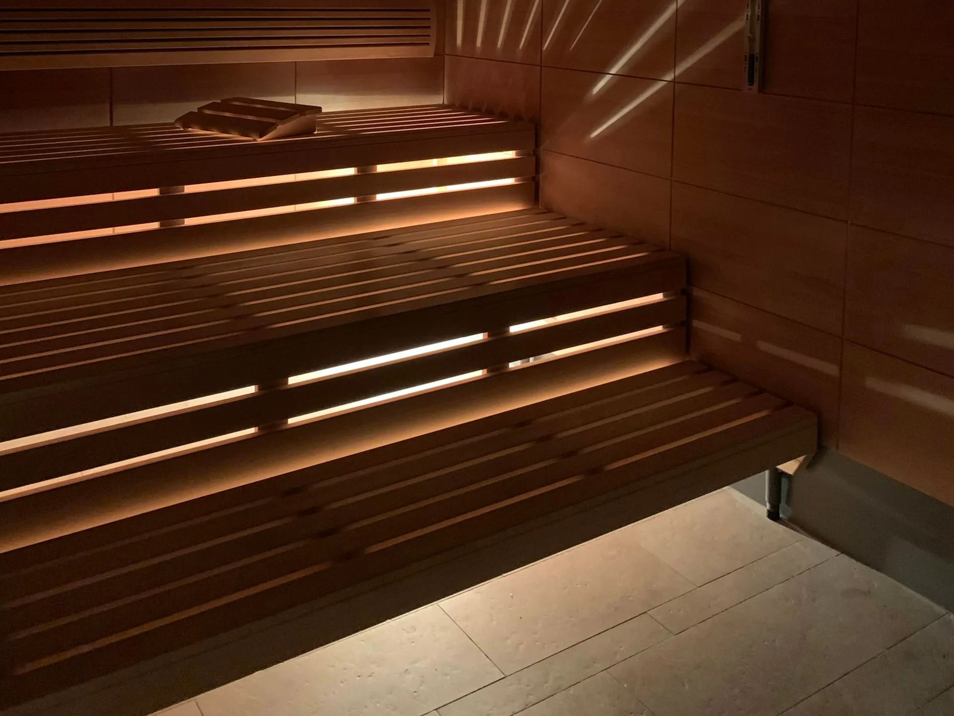 Cedar sauna benching in low light, the finish level a commercial recovery room is specified to