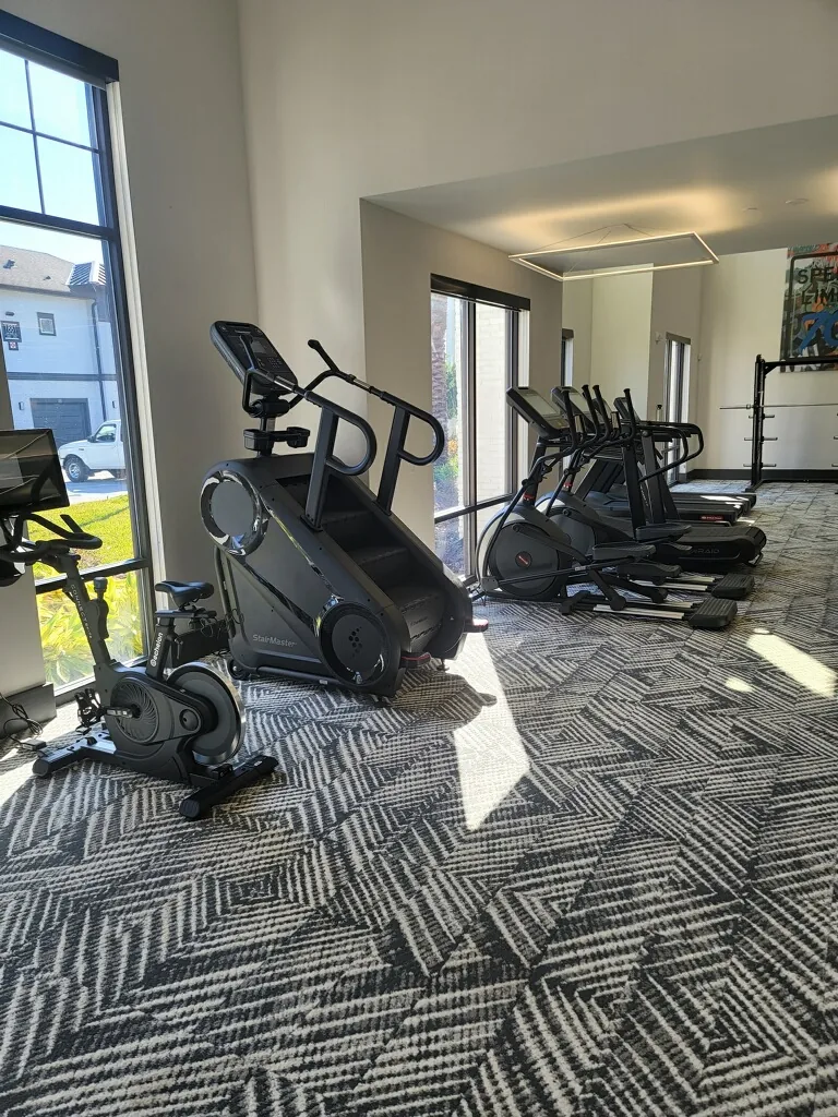 Cardio row in an Apopka, Florida community gym with a StairMaster stepmill, a bike and ellipticals