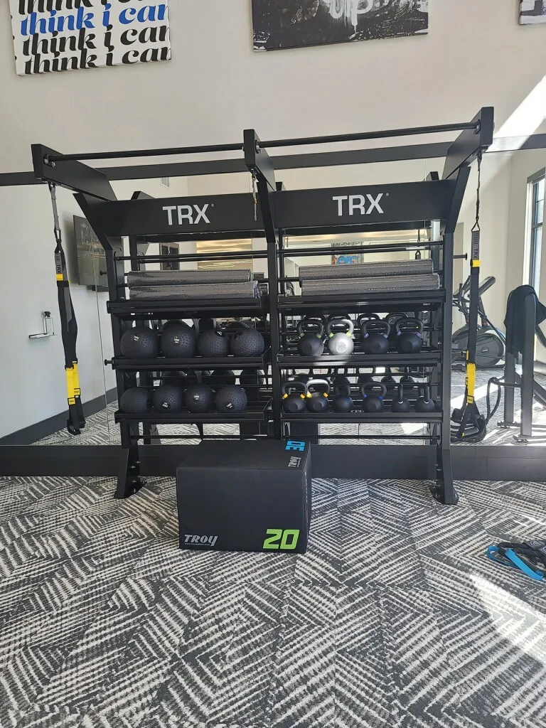 TRX-branded storage rack with kettlebells, slam balls and a plyo box in an Apopka, Florida gym