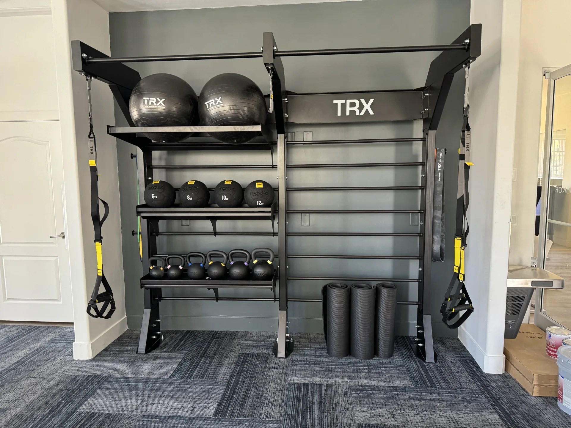Wall-mounted TRX training station with medicine balls and kettlebells at an Arizona apartment amenity gym