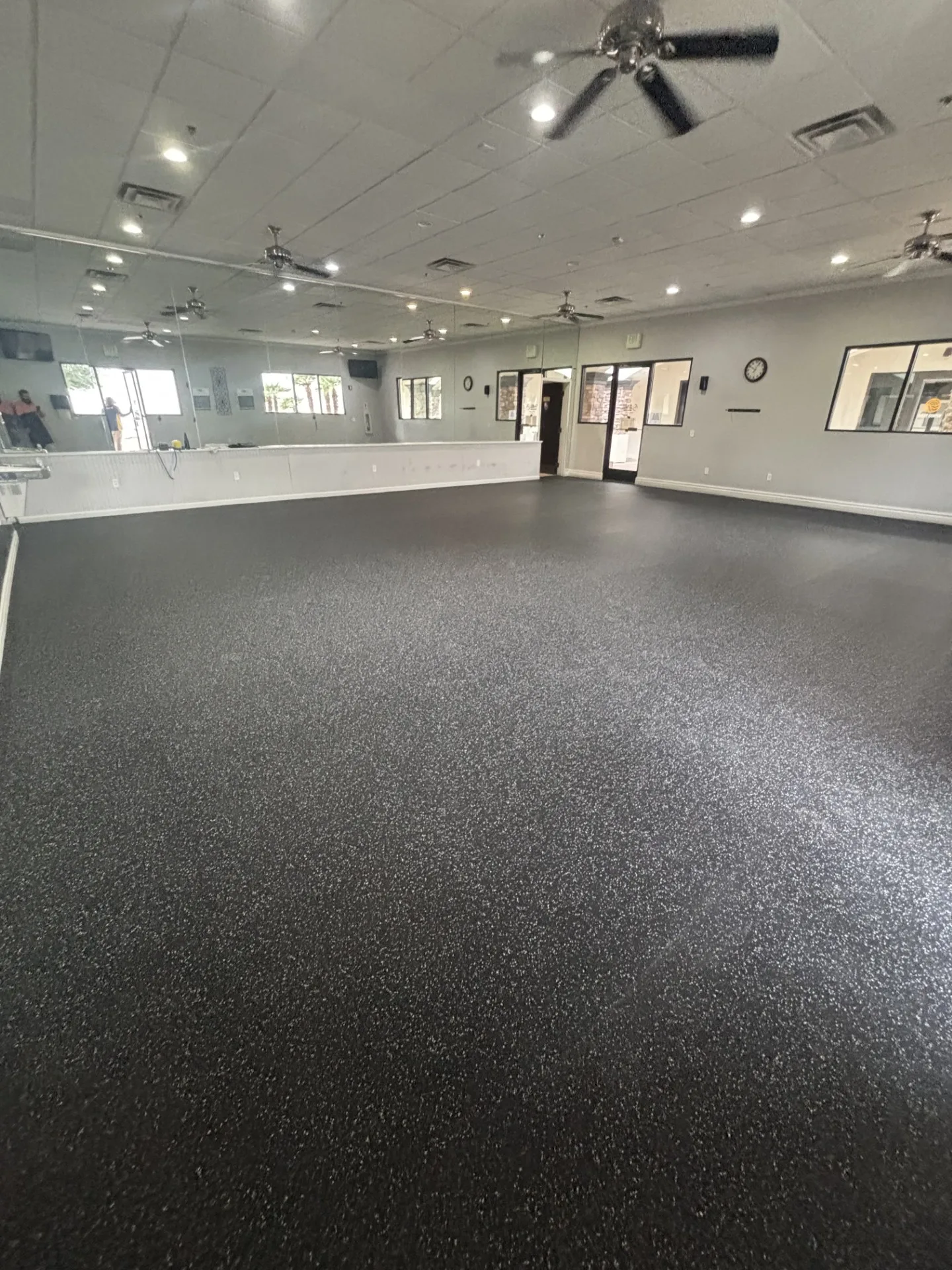 Finished rubber flooring and ceiling fans in an Arizona apartment amenity gym beneath arched windows