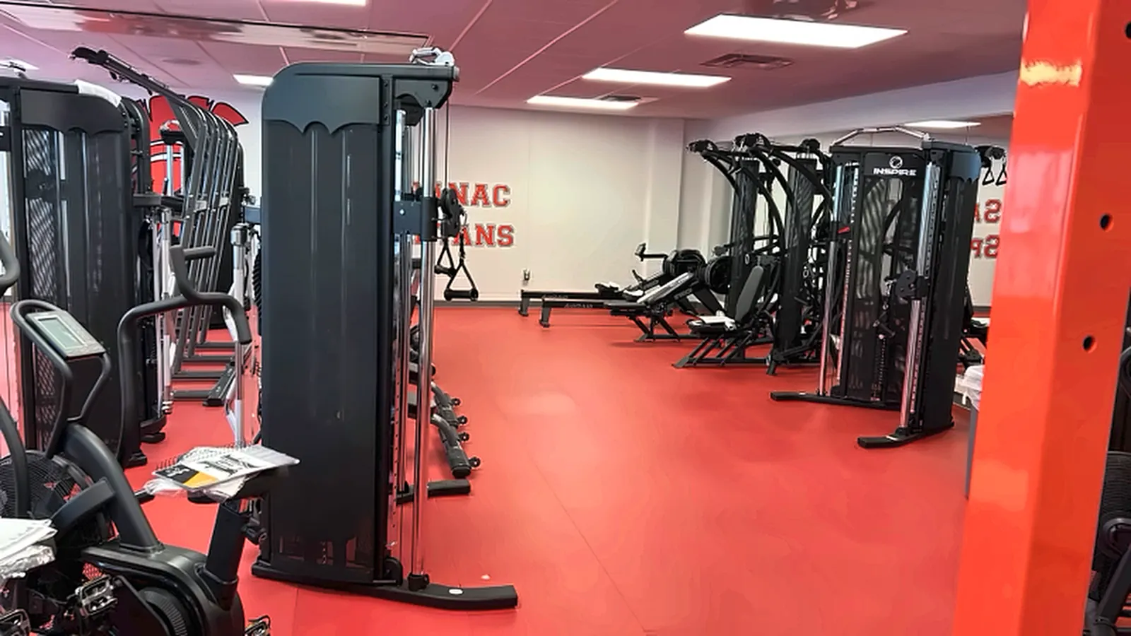 Saranac Central School fitness room in New York: a functional trainer and cable stations on a red rubber floor