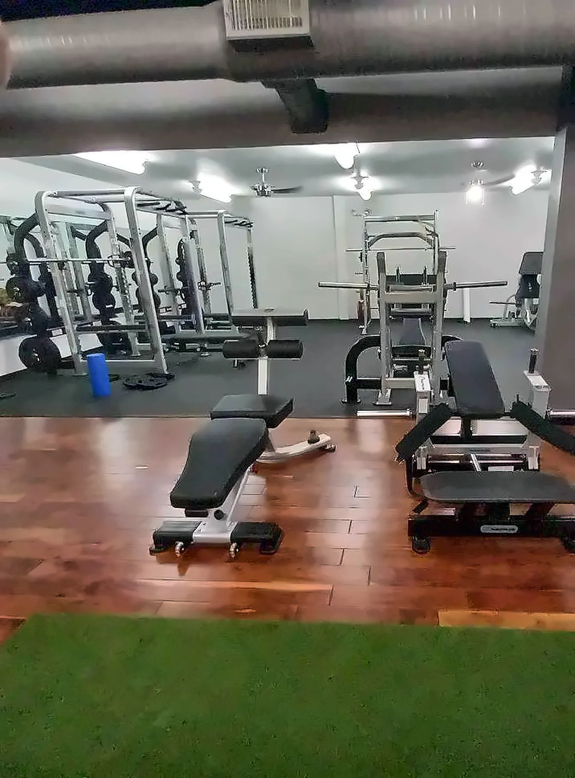 Training Society in Denton, TX: plate-loaded and selectorized strength on a wood-look floor beside a turf strip