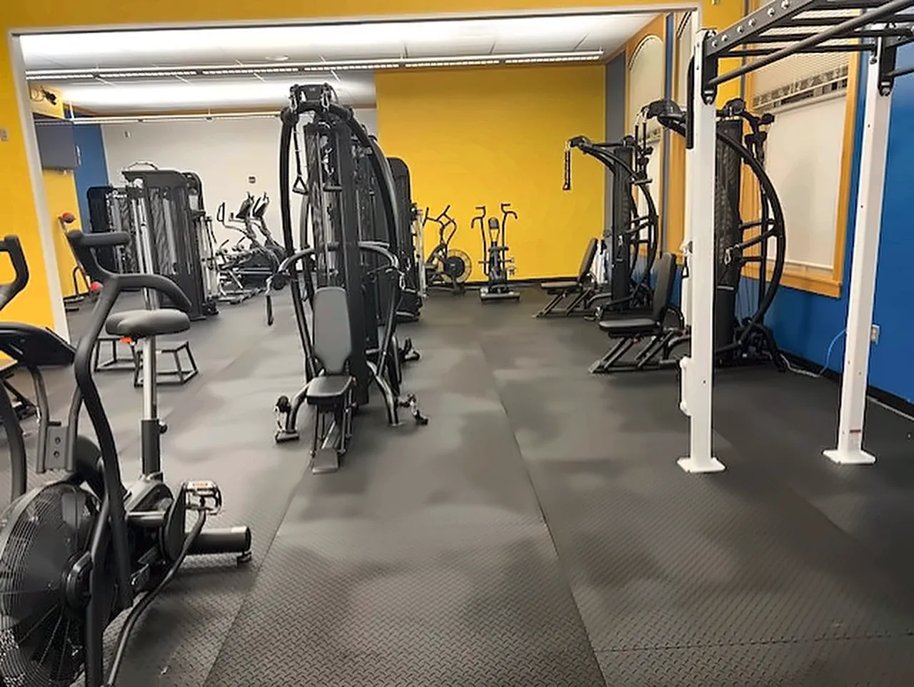 Sheridan Junior High fitness room in Wyoming: an air bike, a multi-gym and functional trainers on rubber mats