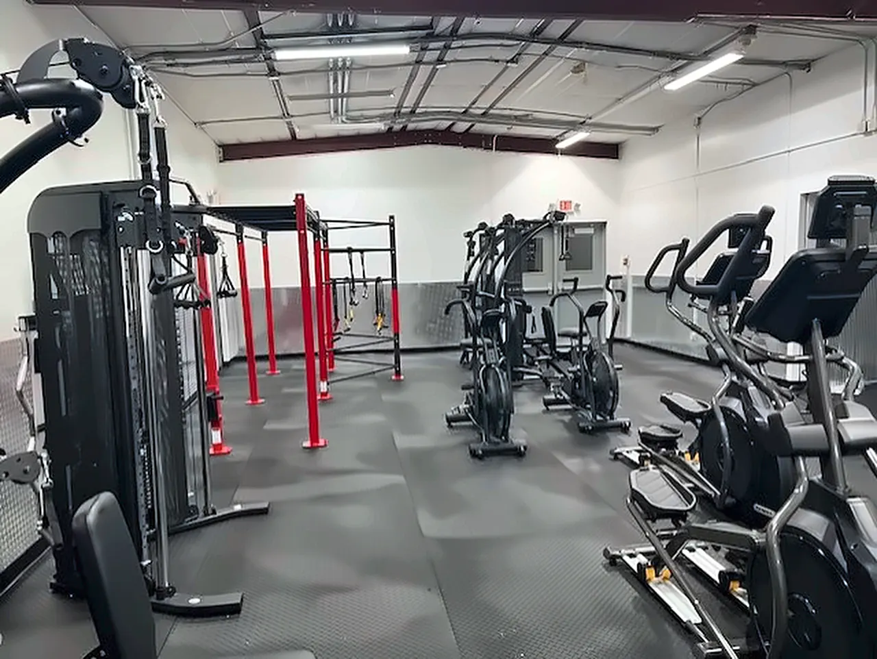 Lander Middle School fitness room in Wyoming: a functional trainer, a red rig, ellipticals and rubber flooring