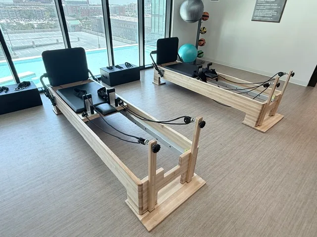Wooden Pilates reformers above a rooftop pool deck in a College Station, Texas student housing studio