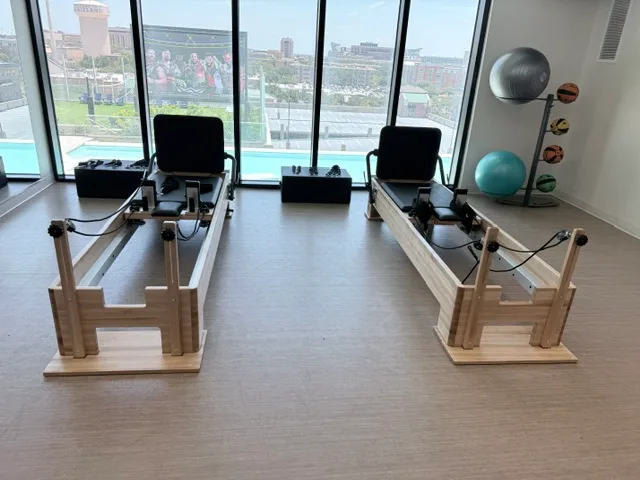 Two Pilates reformers end-on at a window wall with stability balls in a College Station, Texas studio