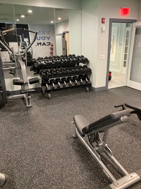 Two-tier dumbbell rack beside a motivational wall graphic at a Danbury, Connecticut apartment gym