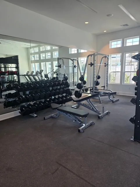 Dumbbell rack, adjustable benches and a half rack reflected in a mirrored wall at a Davenport, Florida apartment gym