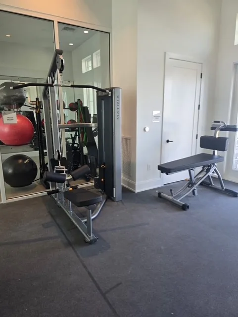 Matrix functional trainer, an adjustable bench and stability balls beside a yoga room at a Davenport, Florida apartment gym