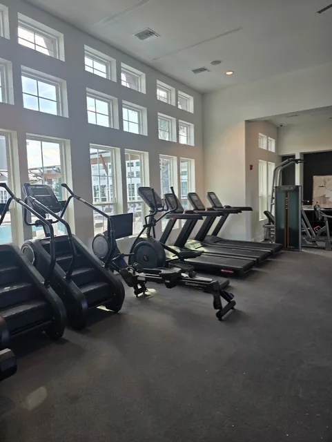 Stair climbers, ellipticals and treadmills along a double-height window wall at a Davenport, Florida apartment gym