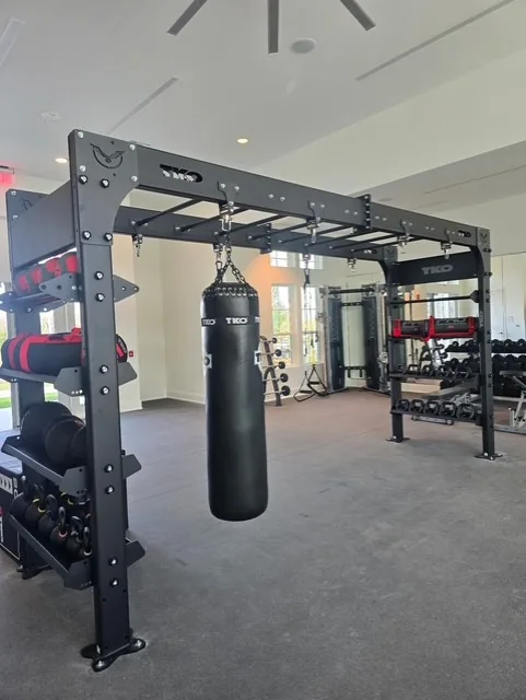 TKO bridge rig with a hanging heavy bag and dumbbell storage at a Davenport, Florida apartment gym