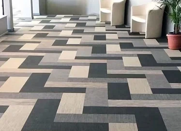 Carpet tile laid in a cream and charcoal brick pattern through a fitness lounge with seating and planting