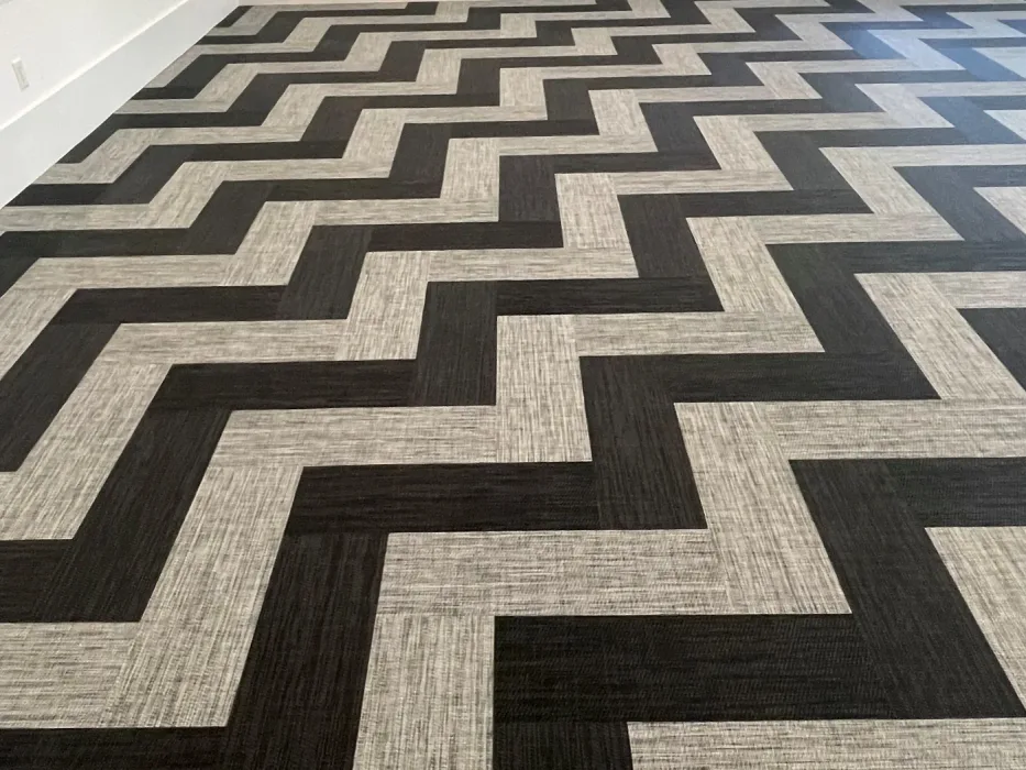 Herringbone woven vinyl in charcoal and oatmeal laid on the diagonal across a mirrored studio with arched windows