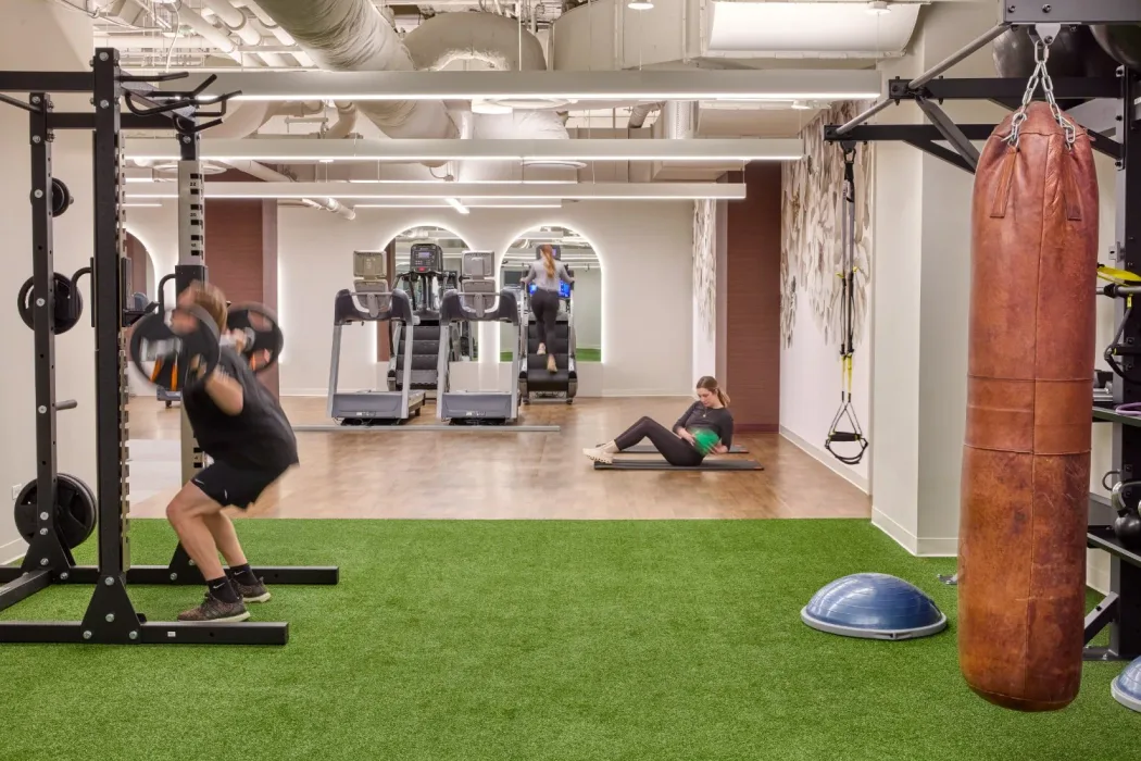 Turf sled lane beside a rack, heavy bag and BOSU in a functional training zone finished in rubber
