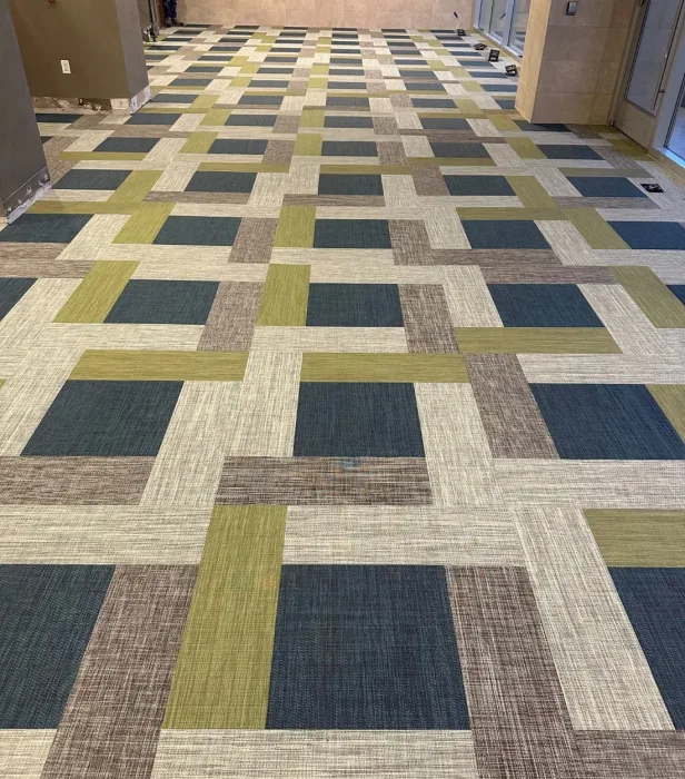 Woven vinyl laid in olive, navy and cream color blocks along a fitness corridor