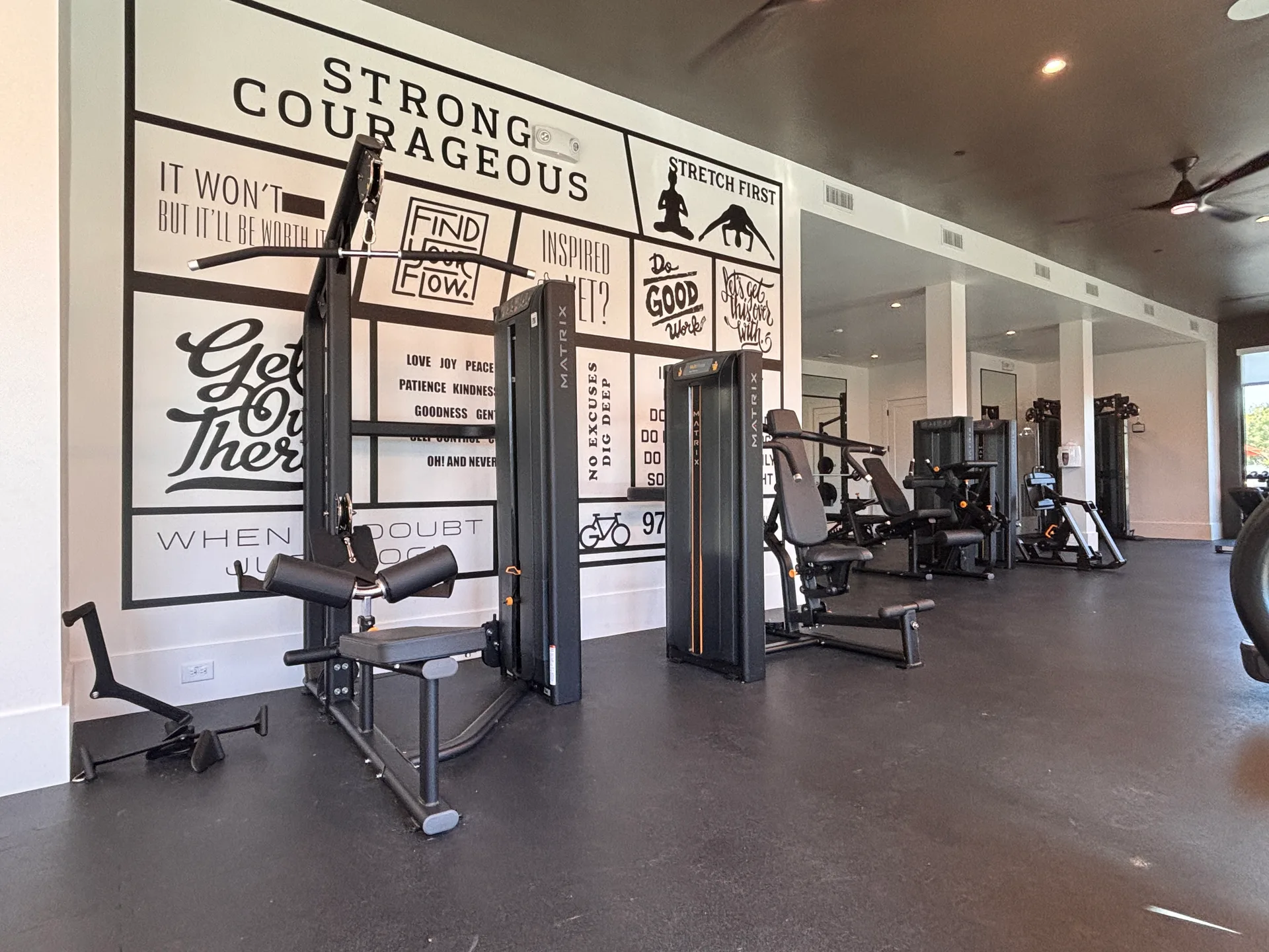 Matrix Versa strength line in front of a black-and-white typographic mural wall in a Grand Prairie, Texas apartment gym