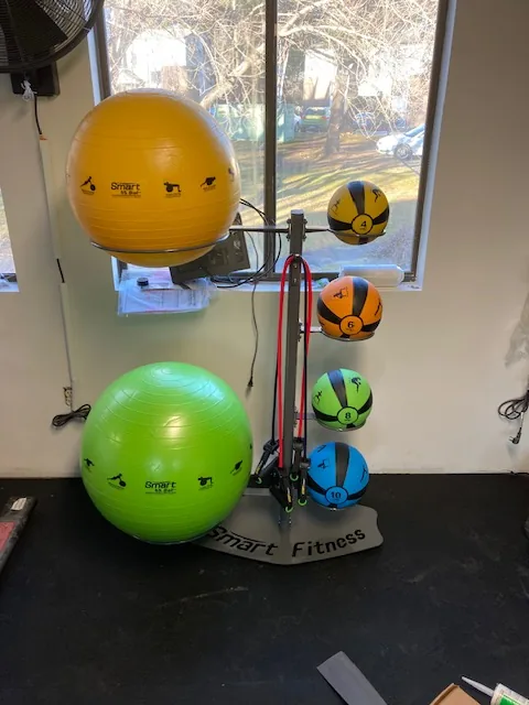 Wall rack of medicine balls, stability balls and resistance bands at a Groton, Connecticut apartment gym