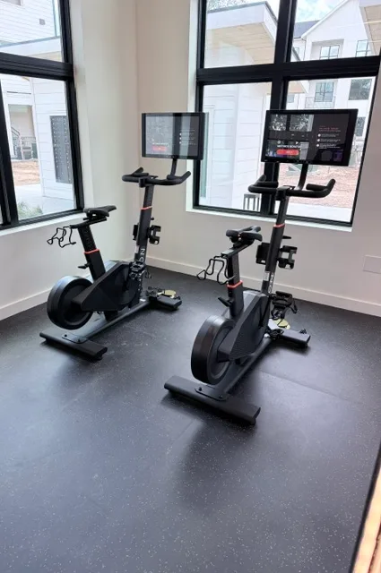 Two Aviron connected bikes with touchscreens at a corner window in a Katy, Texas apartment gym