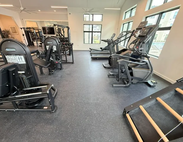 Selectorized leg machine, Jacob's Ladder, climbmill and ellipticals along windows in a Katy, Texas apartment gym