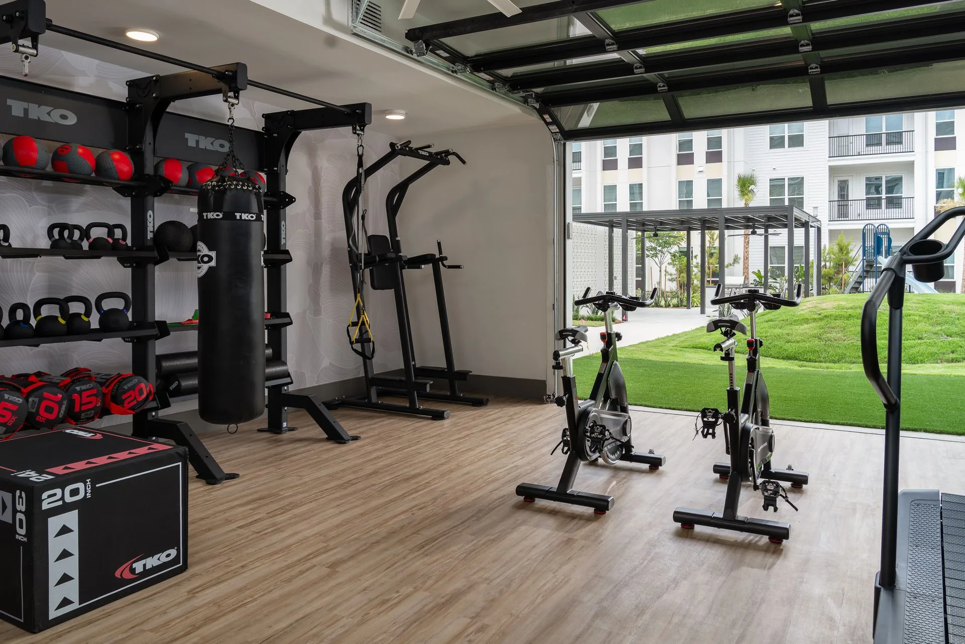 Functional room with a TKO storage wall, heavy bag and indoor cycles, its glass door open to the lawn, in Lutz, Florida